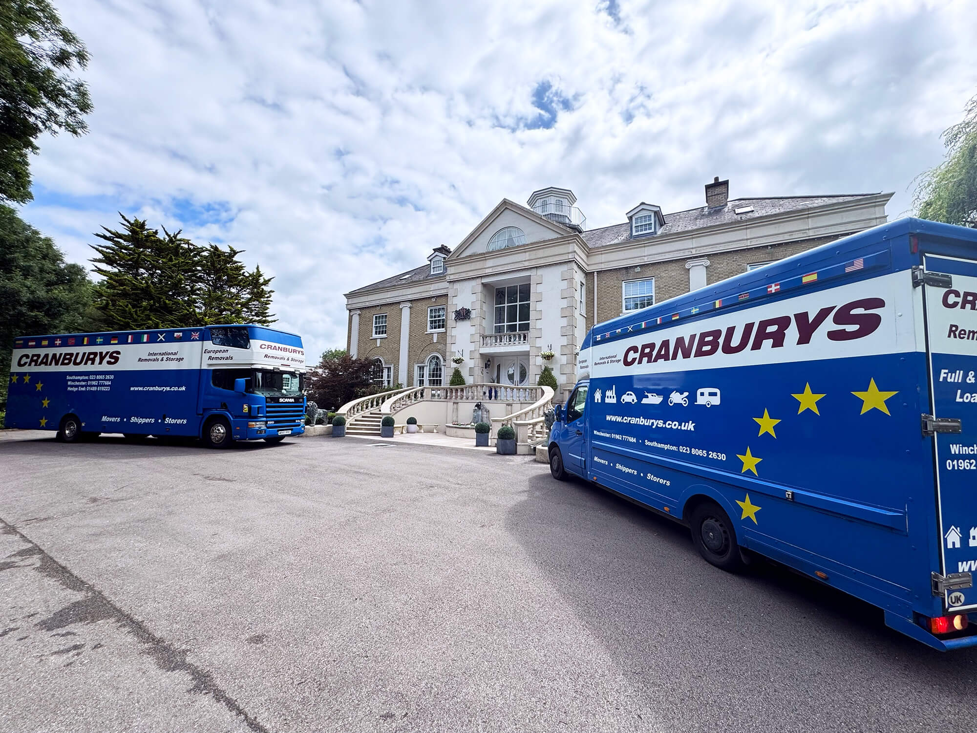 Two Cranburys removals vehicles outside a grand residential home in the UK, showcasing domestic moving services